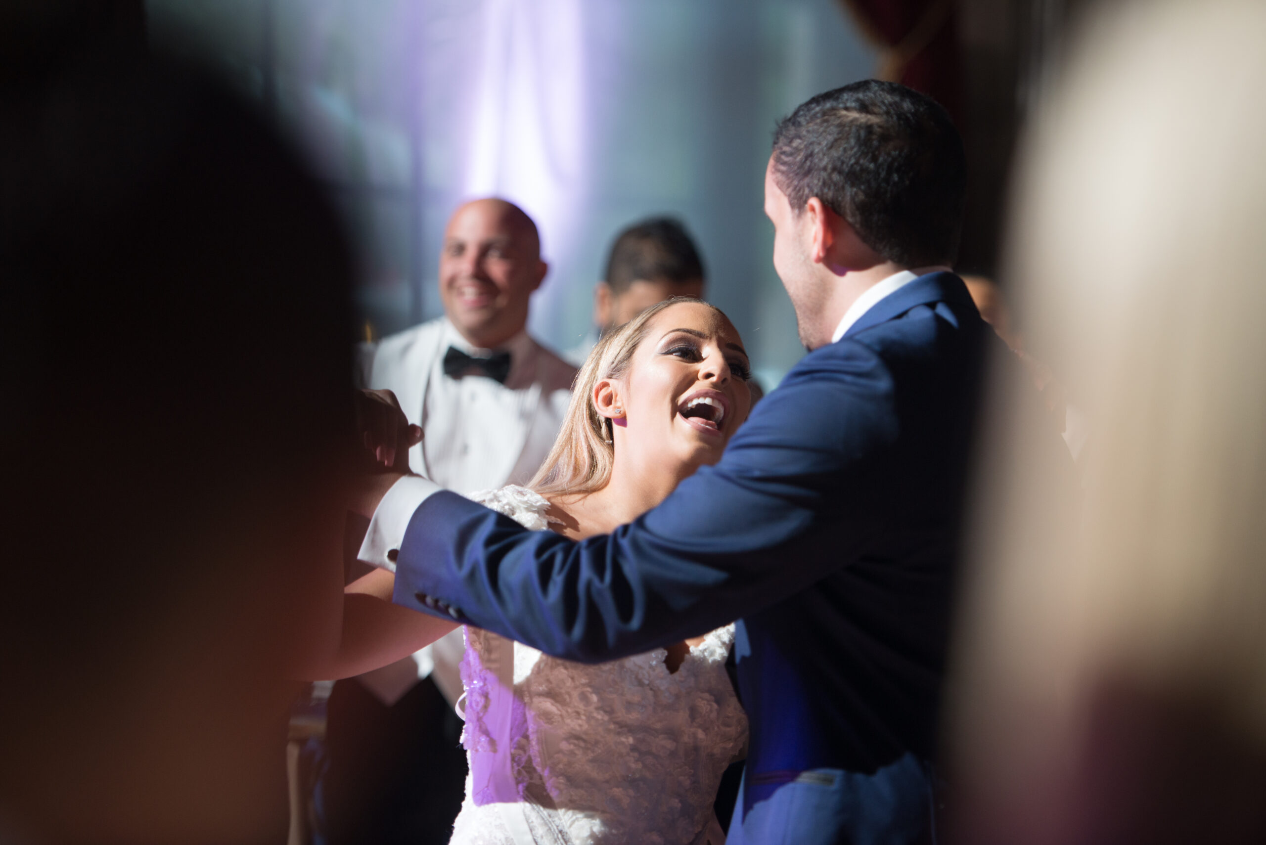 Bride laughing joyfully while dancing with her groom at a Connecticut wedding reception with purple uplighting