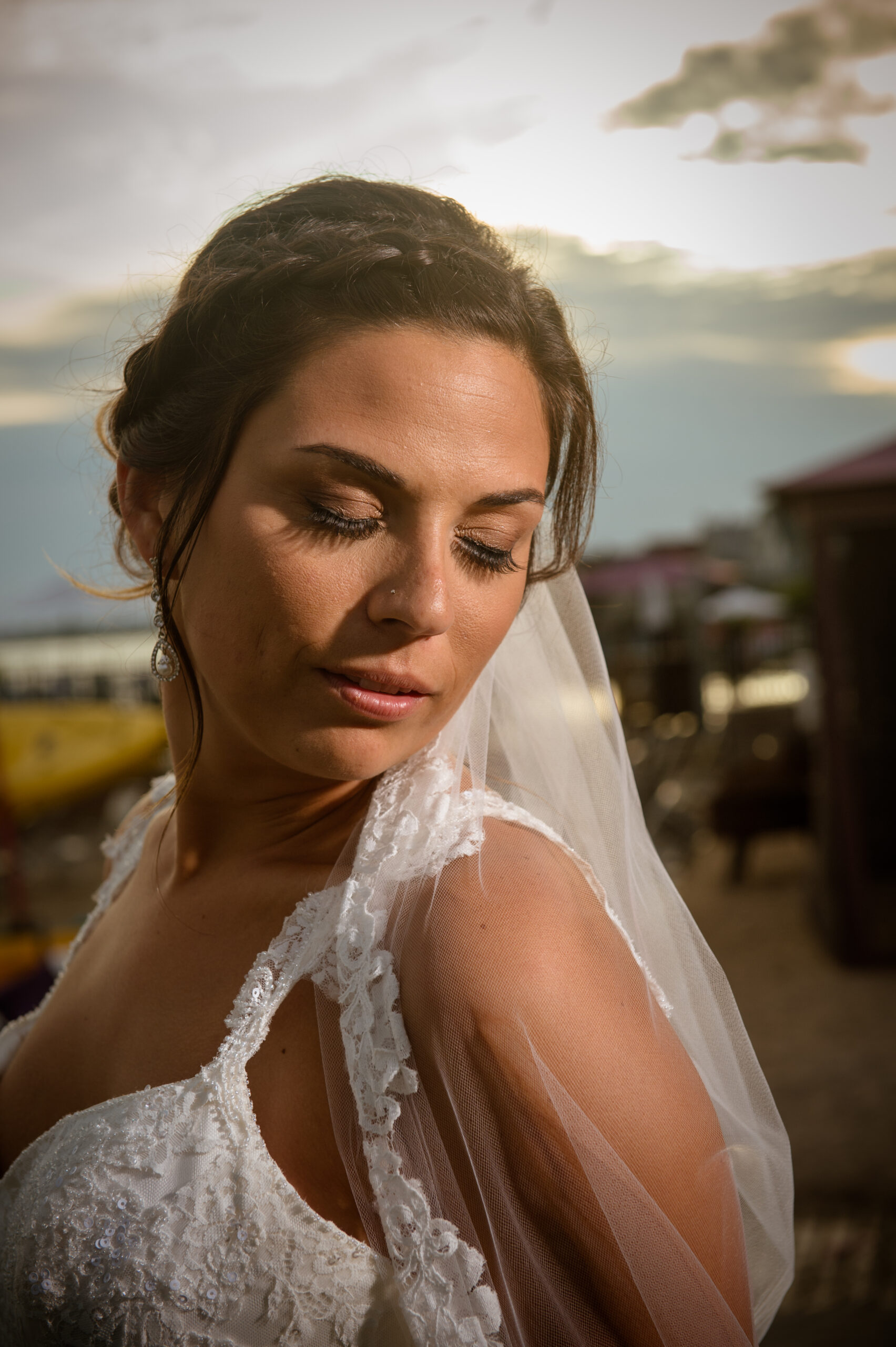 Bride with lace-edged veil looking over her shoulder at sunset at Water's Edge Resort and Spa in Westbrook CT